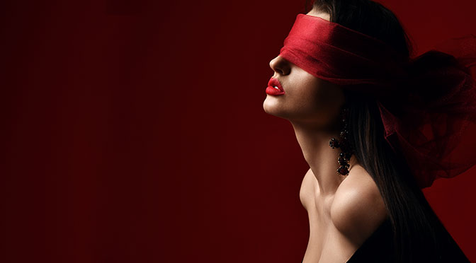 Profil der aufgeregten Frau mit nackten Schultern und Brust hält und Augen mit rotem Schal bedeckt, Augenblende auf dunklem Hintergrund mit Kopienraum. Mode, Vogue, sexy stylische Optik für Frauenkonzept