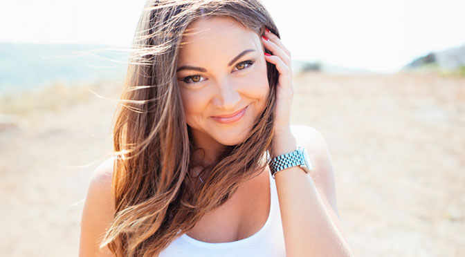 Portrait of the young beautiful smiling woman outdoors enjoying summer sun