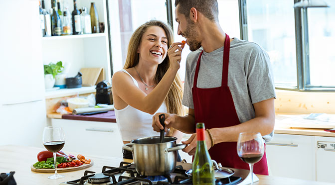 junges verliebtes Paar steht in der Küche und kocht