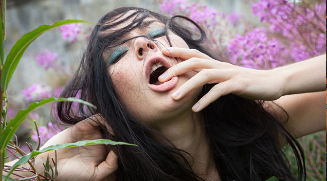 Frau liegt im Freien zwischen Blumen und erlebt einen verzückenden Orgasmus